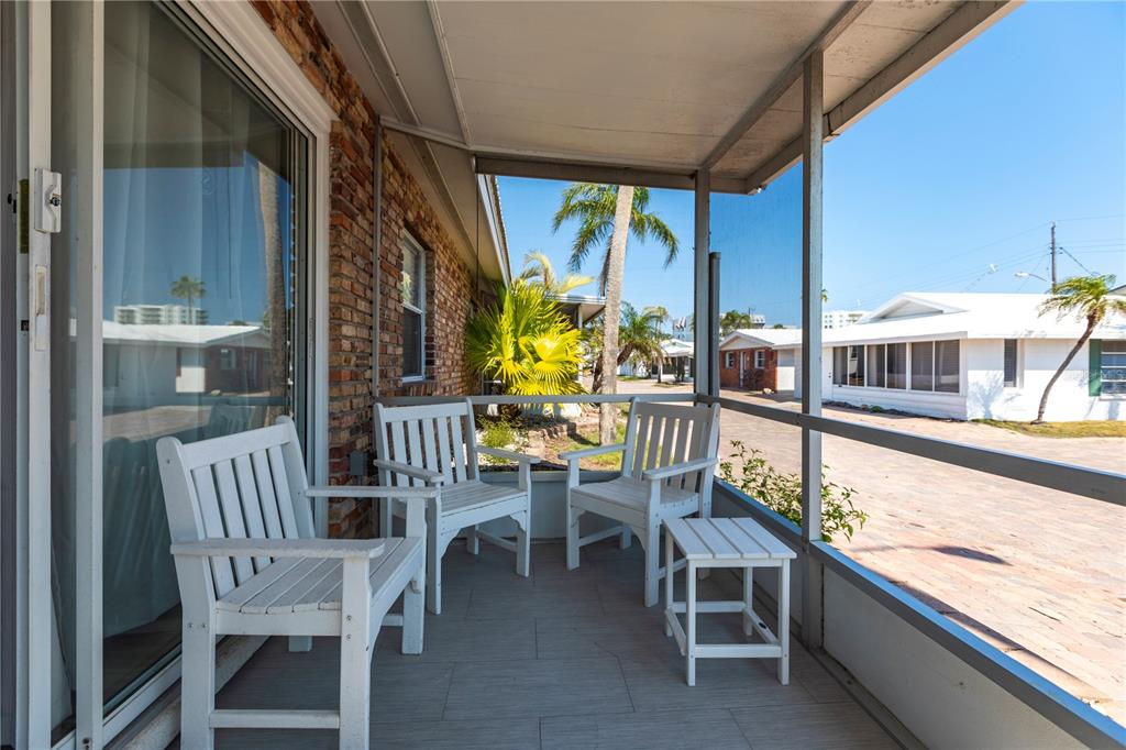 A screened-in porch with white wooden furniture overlooks a paved street and neighboring houses — 6020 MIDNIGHT PASS ROAD UNIT 11, SARASOTA, FL