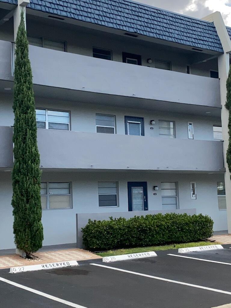 A three-story apartment building exterior features gray walls, blue trim, and reserved parking spaces — 7817 Golf Cir Drive # 210, Margate FL 33063, MARGATE, FL