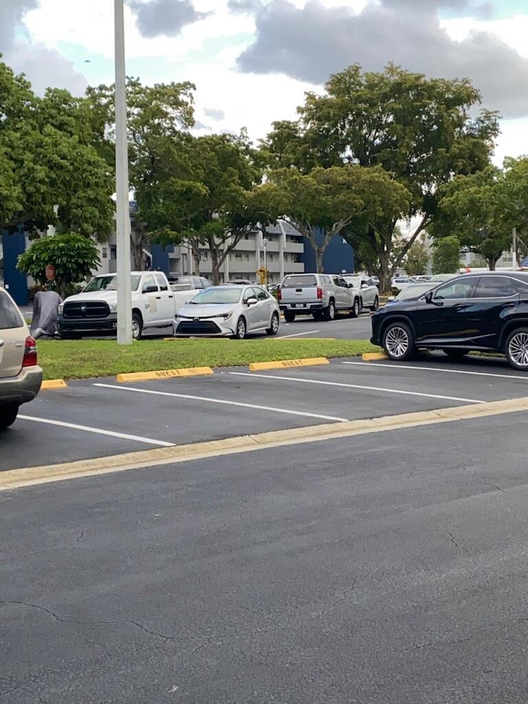 A parking lot with several parked cars and guest spaces in front of an apartment building — 7817 Golf Cir Drive # 210, Margate FL 33063, MARGATE, FL