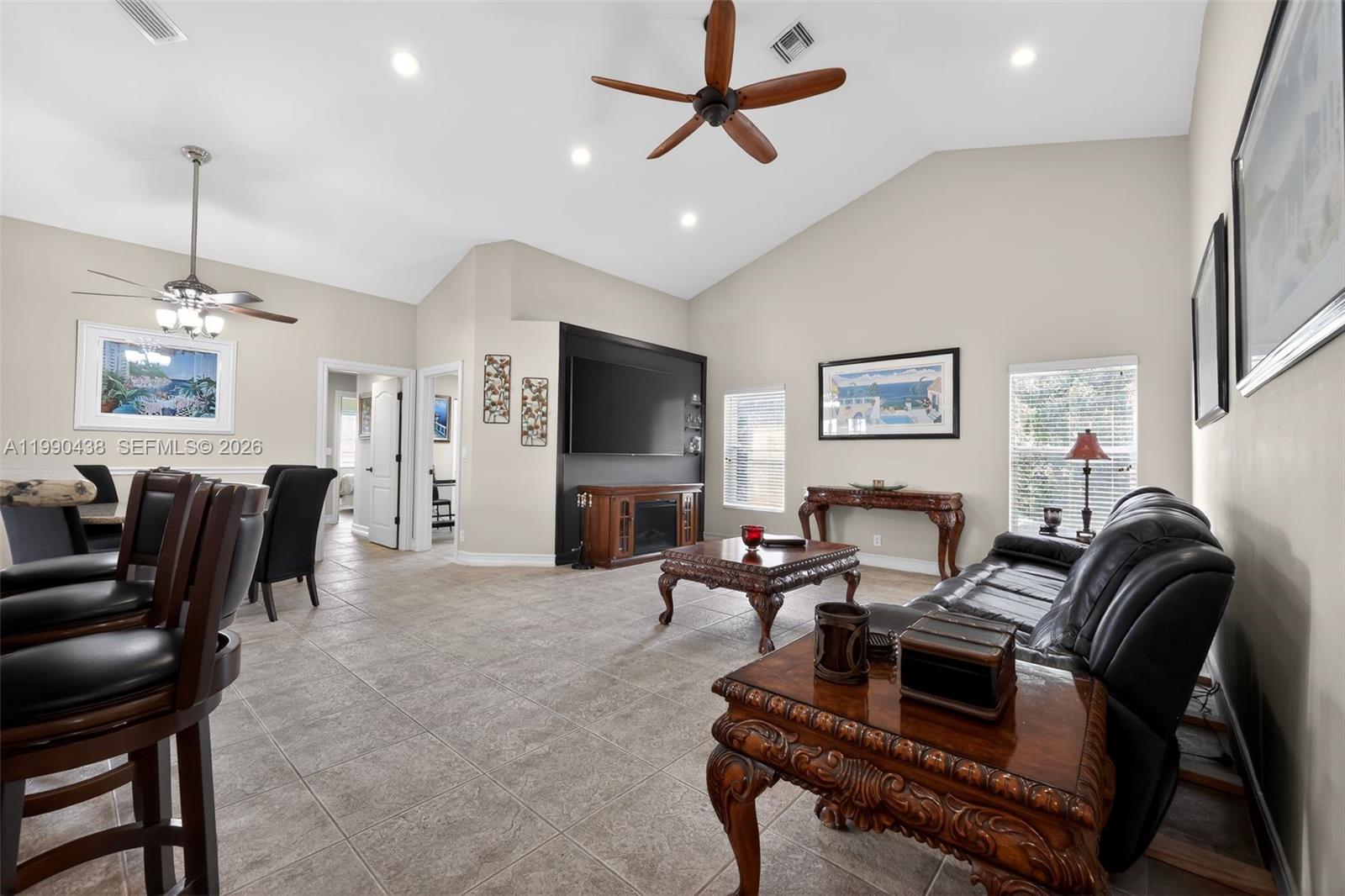 A living room features vaulted ceilings, tile flooring, a black media wall, and dark furniture — 12301 Cabot Ct, Boca Raton FL 33428, BOCA RATON, FL