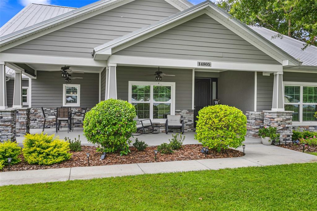 The exterior of a gray house features a covered porch, stone pillars, and manicured landscaping — 14805 SYDNEY HEIGHTS COURT, DOVER, FL
