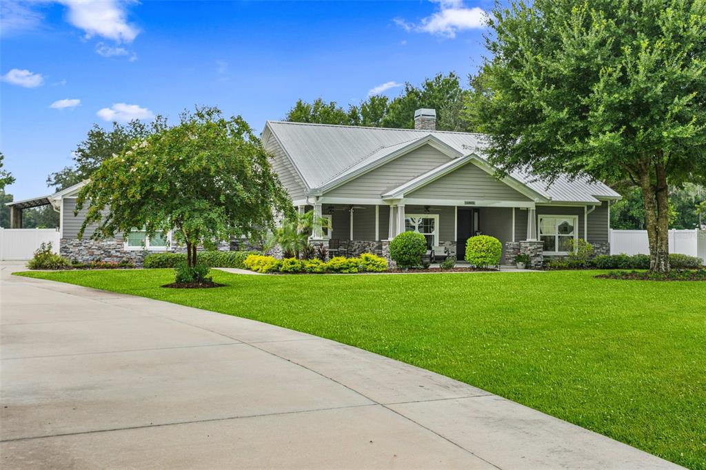 A single-story house with a metal roof, stone accents, and a large front lawn — 14805 SYDNEY HEIGHTS COURT, DOVER, FL