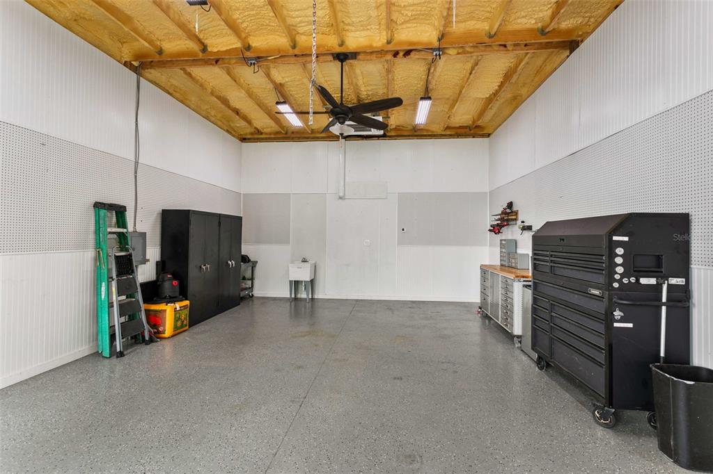 A spacious garage with a speckled concrete floor, exposed ceiling insulation, and metal storage cabinets — 14805 SYDNEY HEIGHTS COURT, DOVER, FL