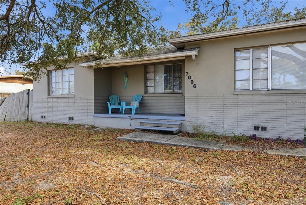 A living room with hardwood floors, a white brick wall, and an adjacent dining area — 7096 54TH AVENUE N, ST PETERSBURG, FL