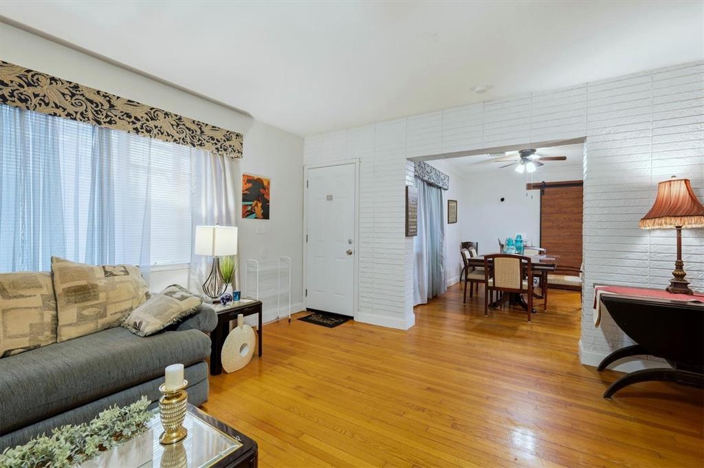 A white brick wall separates a front entryway from a dining room with hardwood floors — 7096 54TH AVENUE N, ST PETERSBURG, FL