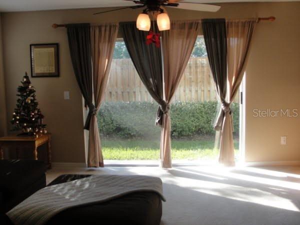 A living room features a sliding glass door with layered curtains and a small Christmas tree — 2537 HARN BOULEVARD UNIT 1, CLEARWATER, FL