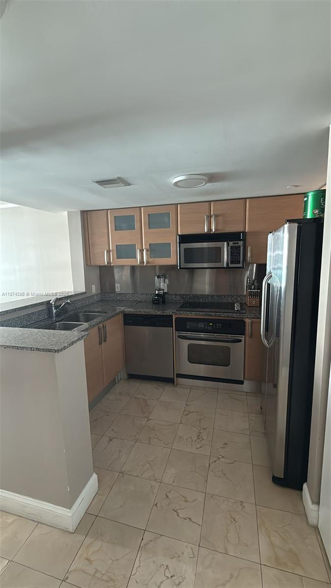 A kitchen features light wood cabinets, stainless steel appliances, and a granite countertop — 2101 Brickell Ave # 508, Miami FL 33129, MIAMI, FL