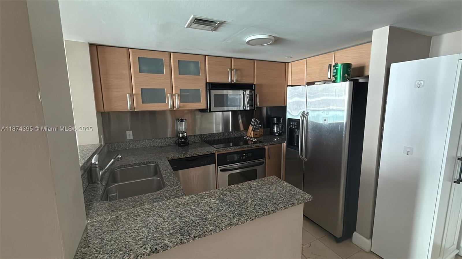 A kitchen features light wood cabinets, granite countertops, and stainless steel appliances — 2101 Brickell Ave # 508, Miami FL 33129, MIAMI, FL