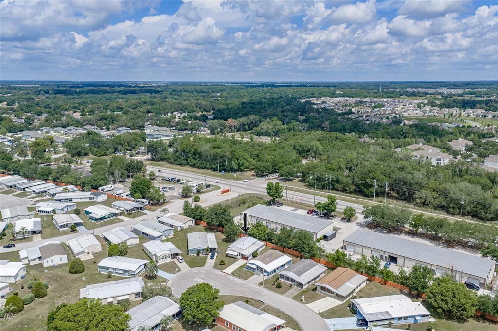 An aerial view shows a residential neighborhood with mobile homes and nearby commercial buildings — 35921 TANDA CIRCLE, ZEPHYRHILLS, FL