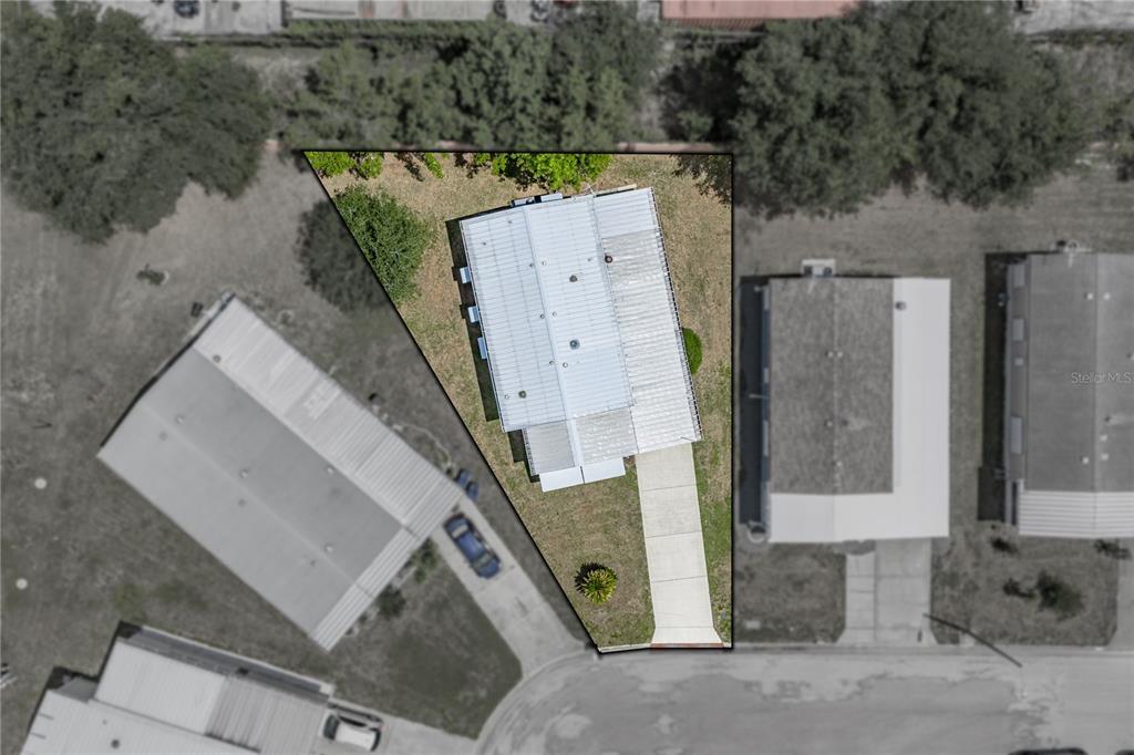 This is an aerial view of a house with a metal roof and driveway — 35921 TANDA CIRCLE, ZEPHYRHILLS, FL