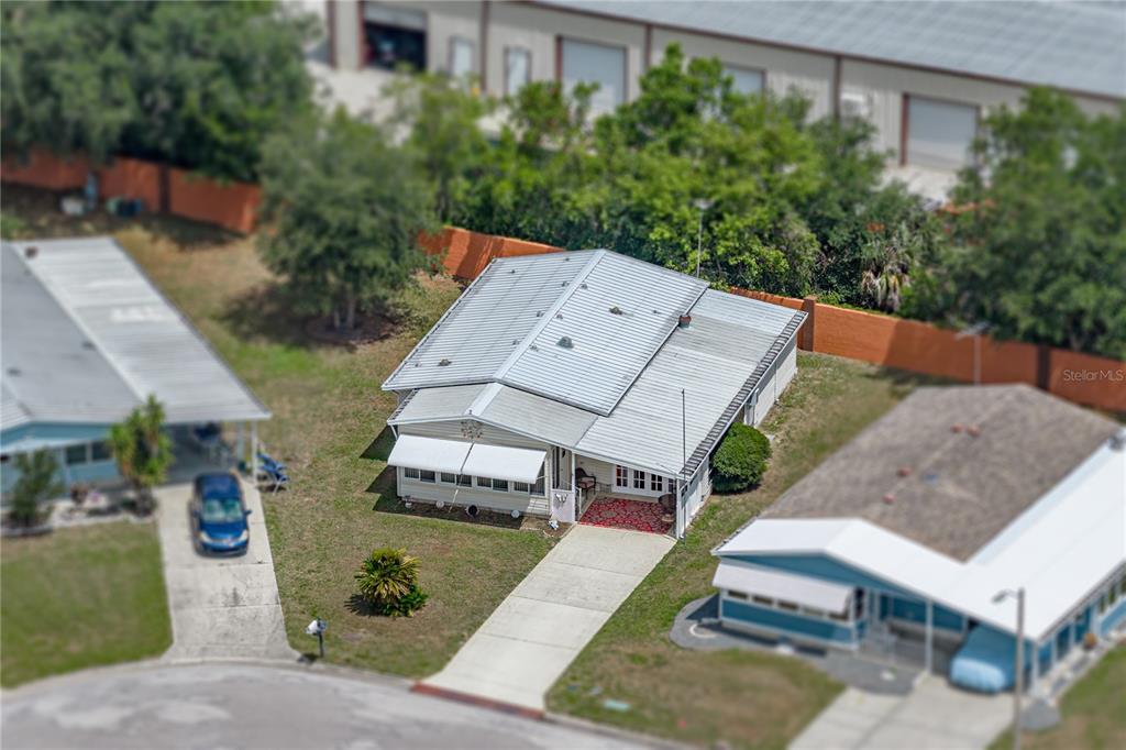 An aerial view shows a single-story house with a metal roof and a concrete driveway — 35921 TANDA CIRCLE, ZEPHYRHILLS, FL