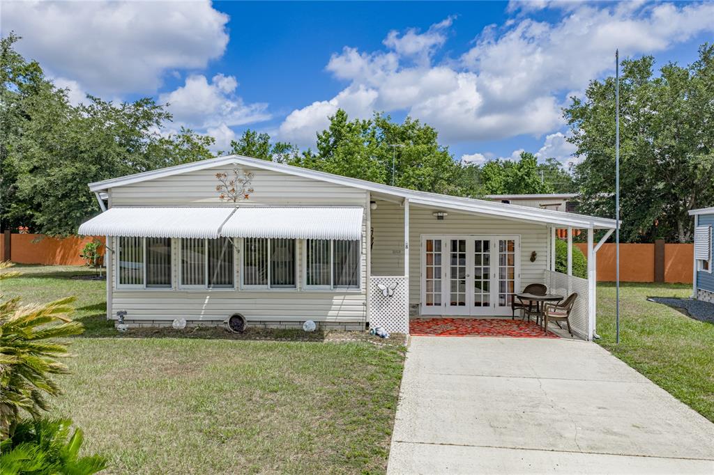 A single-story manufactured home with a white metal awning, a carport, and a concrete driveway — 35921 TANDA CIRCLE, ZEPHYRHILLS, FL