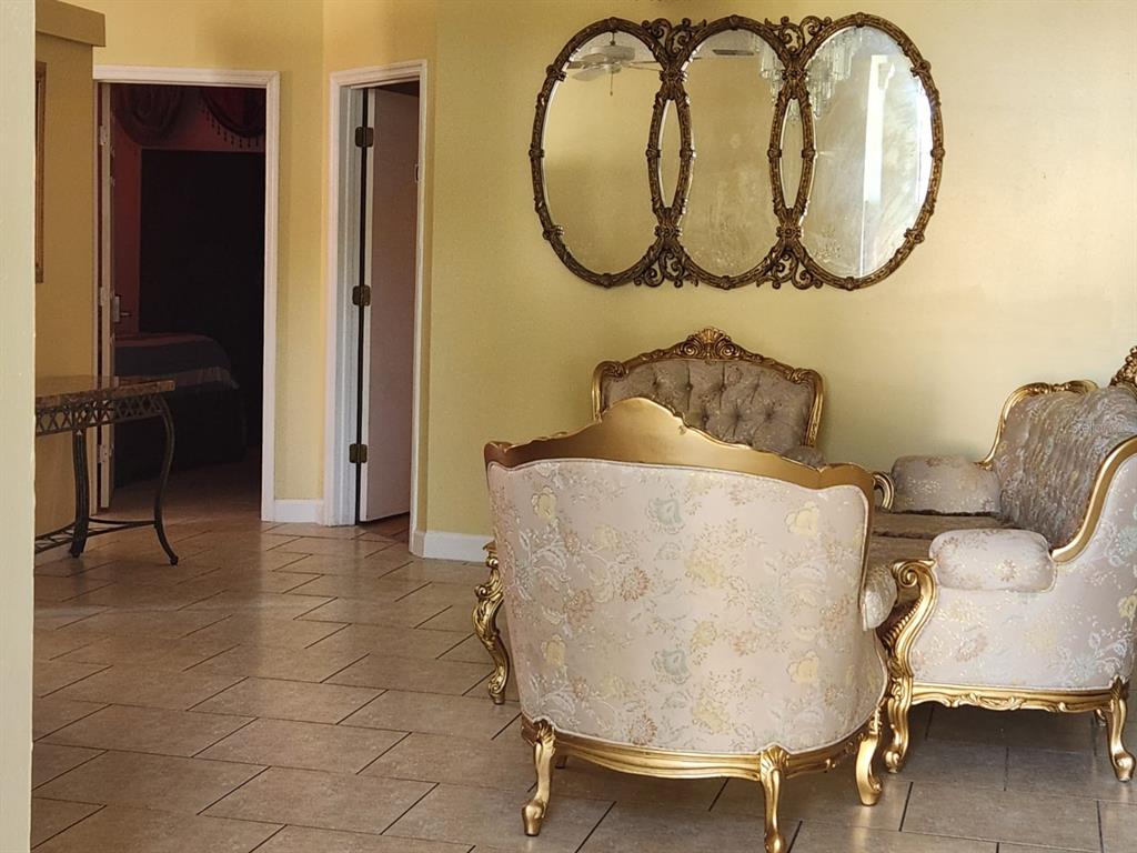 A living room features ornate gold-framed furniture, a triple-pane mirror, and light-colored tile flooring — 12210 HATFIELD COURT, ORLANDO, FL