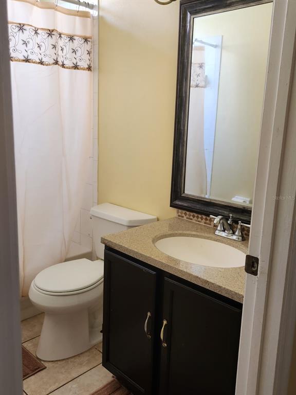 A bathroom features a dark vanity with a stone countertop, a mirror, and a toilet — 12210 HATFIELD COURT, ORLANDO, FL