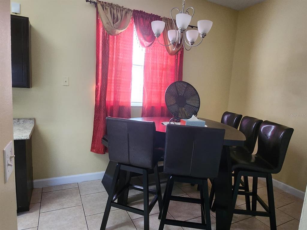 A dining area features a dark table with four chairs, a chandelier, and red curtains — 12210 HATFIELD COURT, ORLANDO, FL