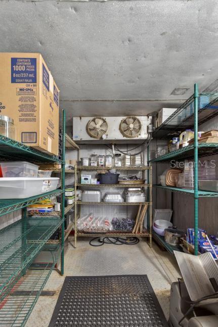 A walk-in cooler with wire shelving units, storage containers, and a dual-fan refrigeration unit — 9824 US HWY 19 HIGHWAY, PORT RICHEY, FL