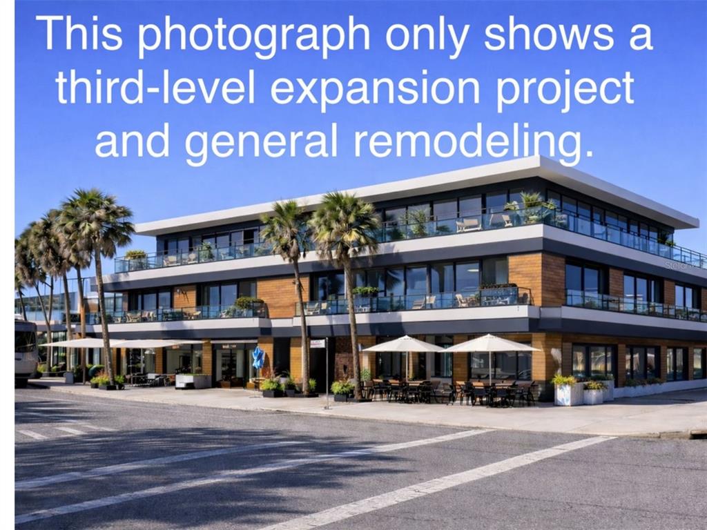 A three-story building with wood siding, glass balconies, and outdoor patio seating at street level — 40 S BLVD OF THE PRESIDENTS, SARASOTA, FL