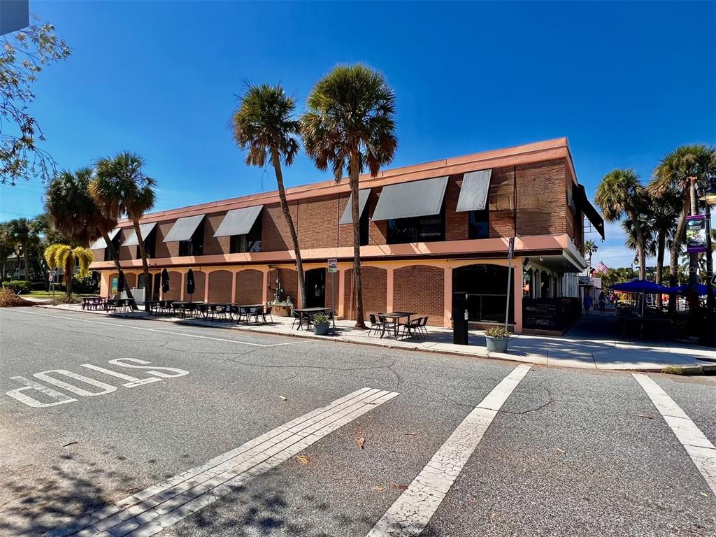 A two-story brick commercial building features outdoor seating, awnings, and palm trees along the street — 40 S BLVD OF THE PRESIDENTS, SARASOTA, FL