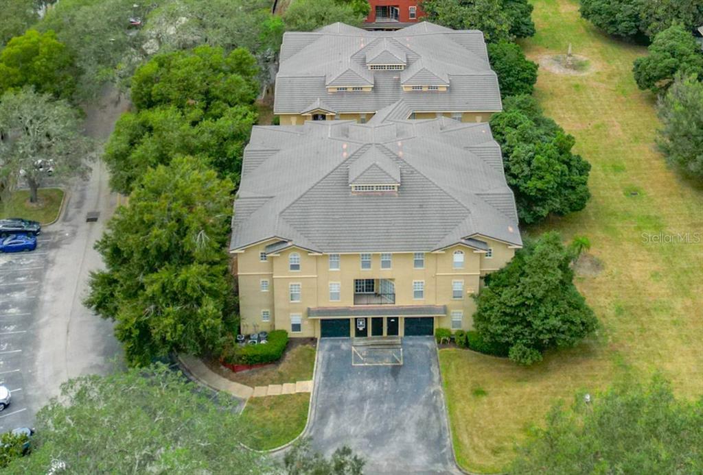 An aerial view of a multi-story tan apartment building with a gray tiled roof — 114 VISTA VERDI CIRCLE UNIT 328, LAKE MARY, FL