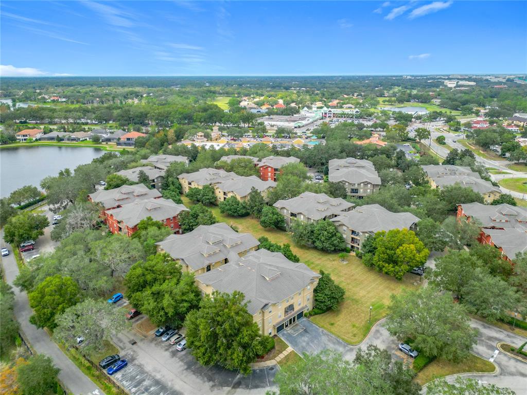 An aerial view shows multiple multi-story apartment buildings surrounded by trees, parking lots, and greenery — 114 VISTA VERDI CIRCLE UNIT 328, LAKE MARY, FL