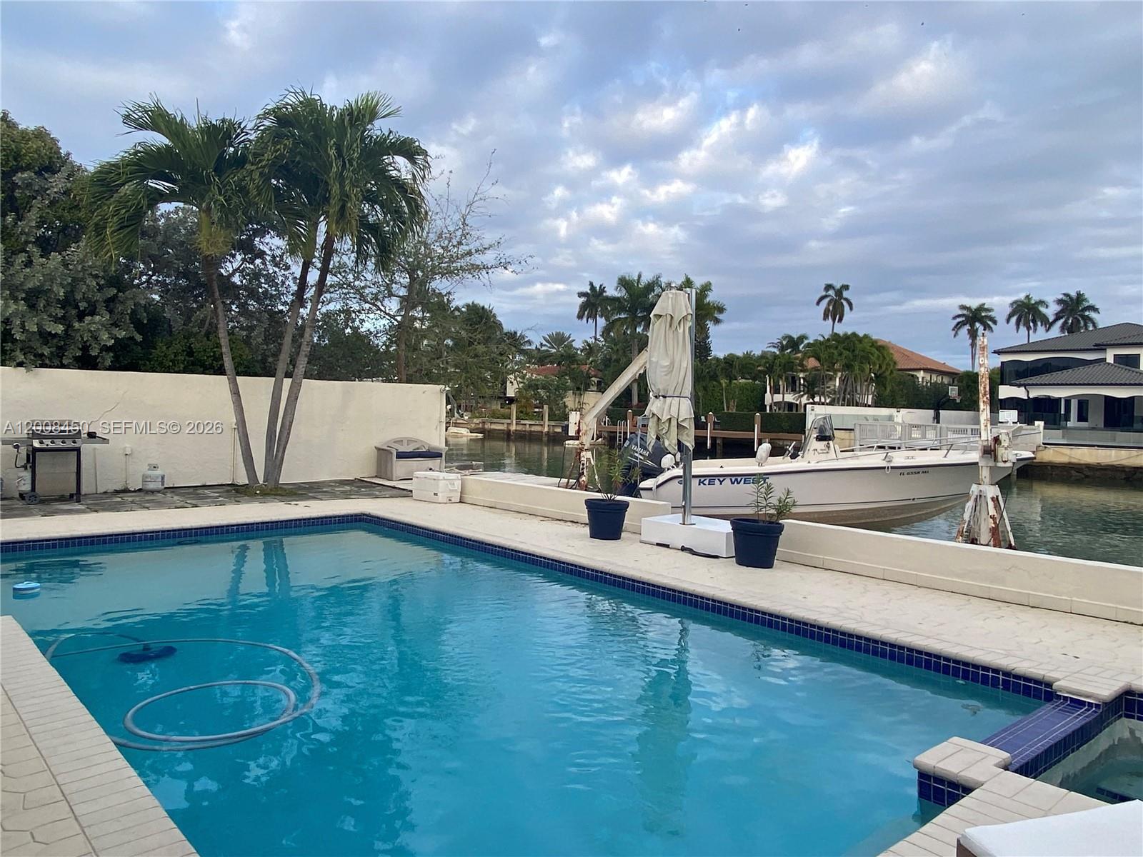 A swimming pool sits on a patio next to a canal with a docked boat — 3485 N Meridian Ave, Miami Beach FL 33140, MIAMI BEACH, FL