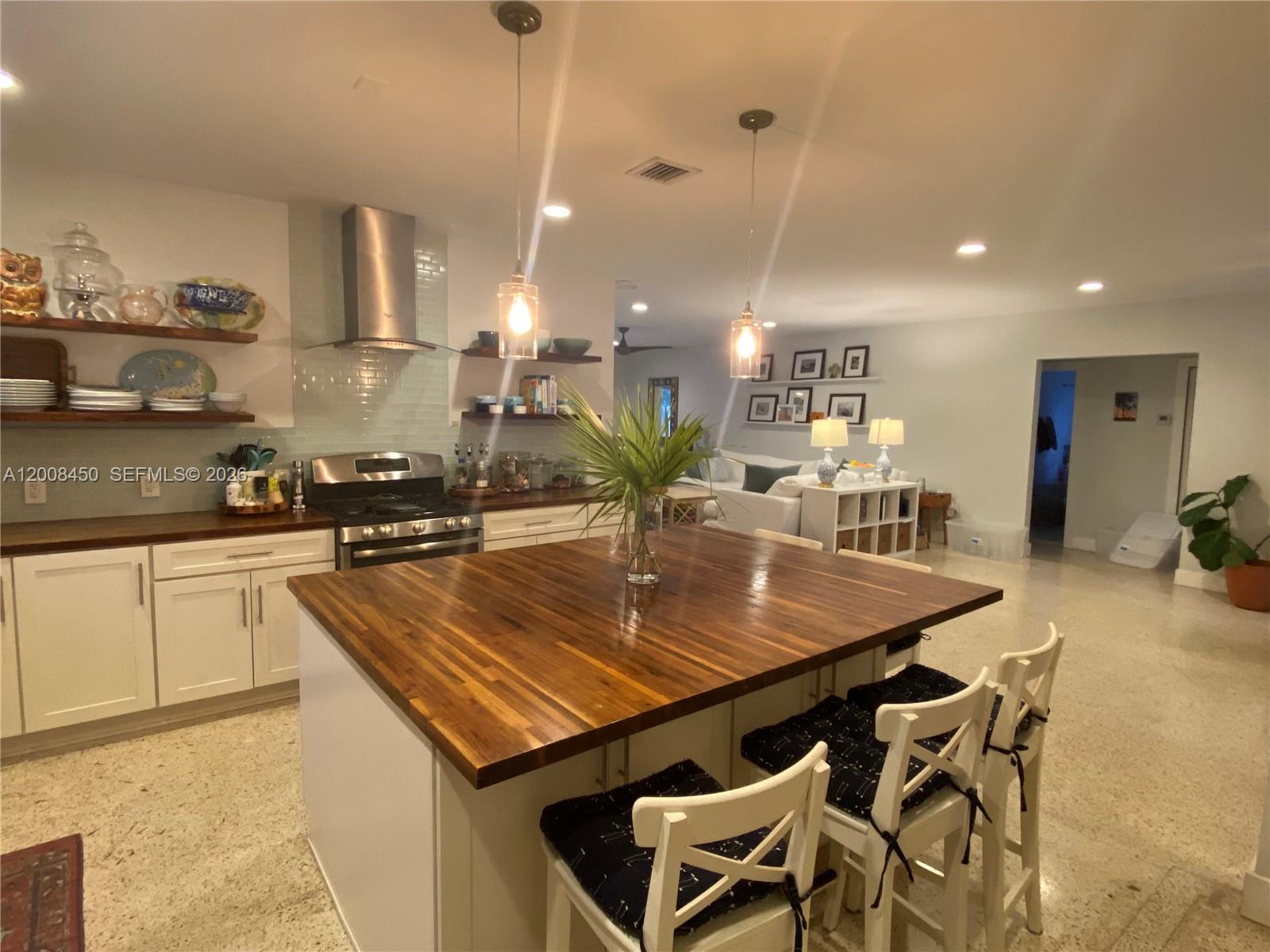A kitchen features a large wooden island, white cabinetry, and open shelving — 3485 N Meridian Ave, Miami Beach FL 33140, MIAMI BEACH, FL