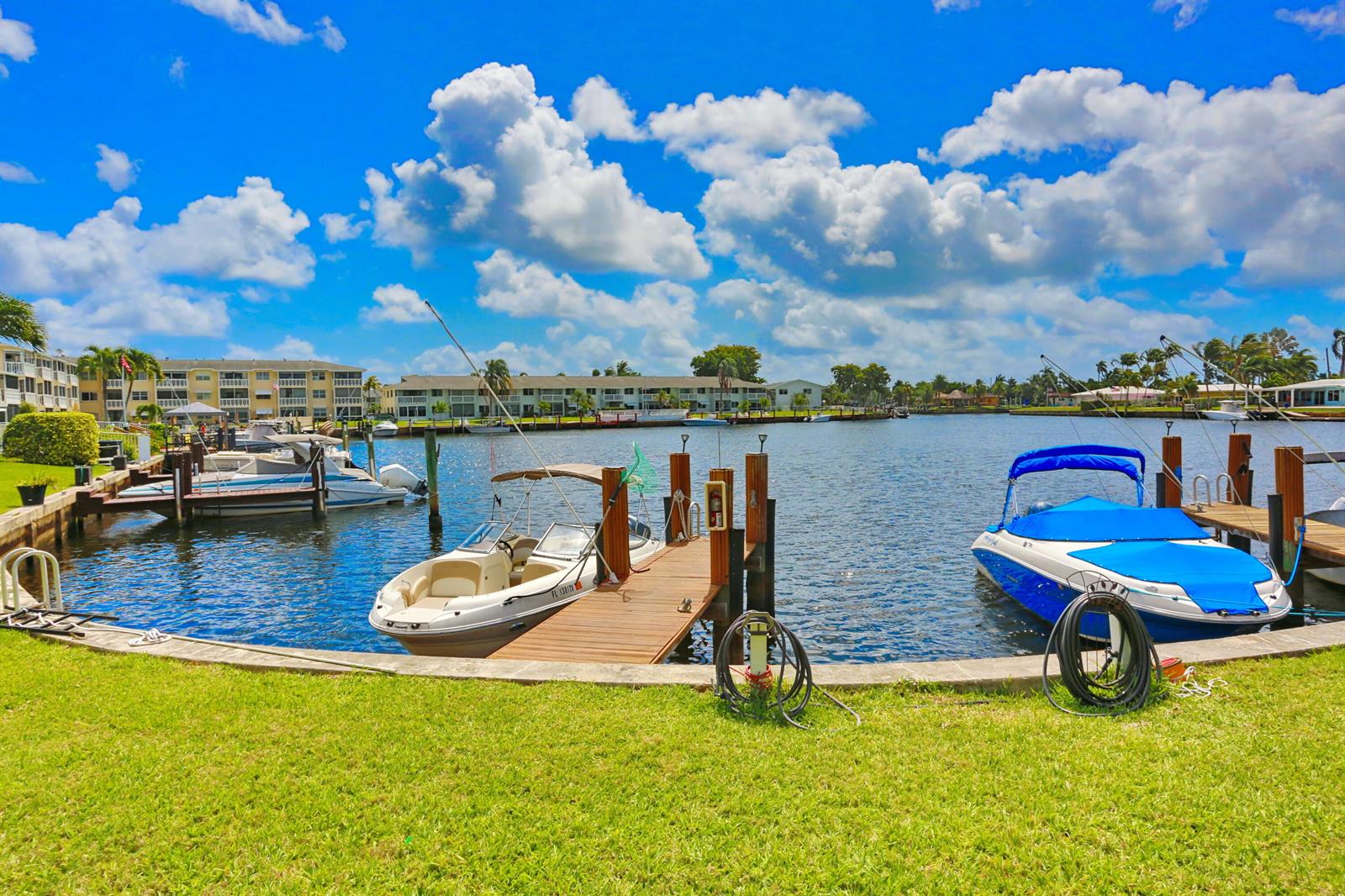 A view of a canal with two boats docked at wooden piers near grassy banks — 600 Pine Drive # 209, Pompano Beach FL 33060, POMPANO BEACH, FL