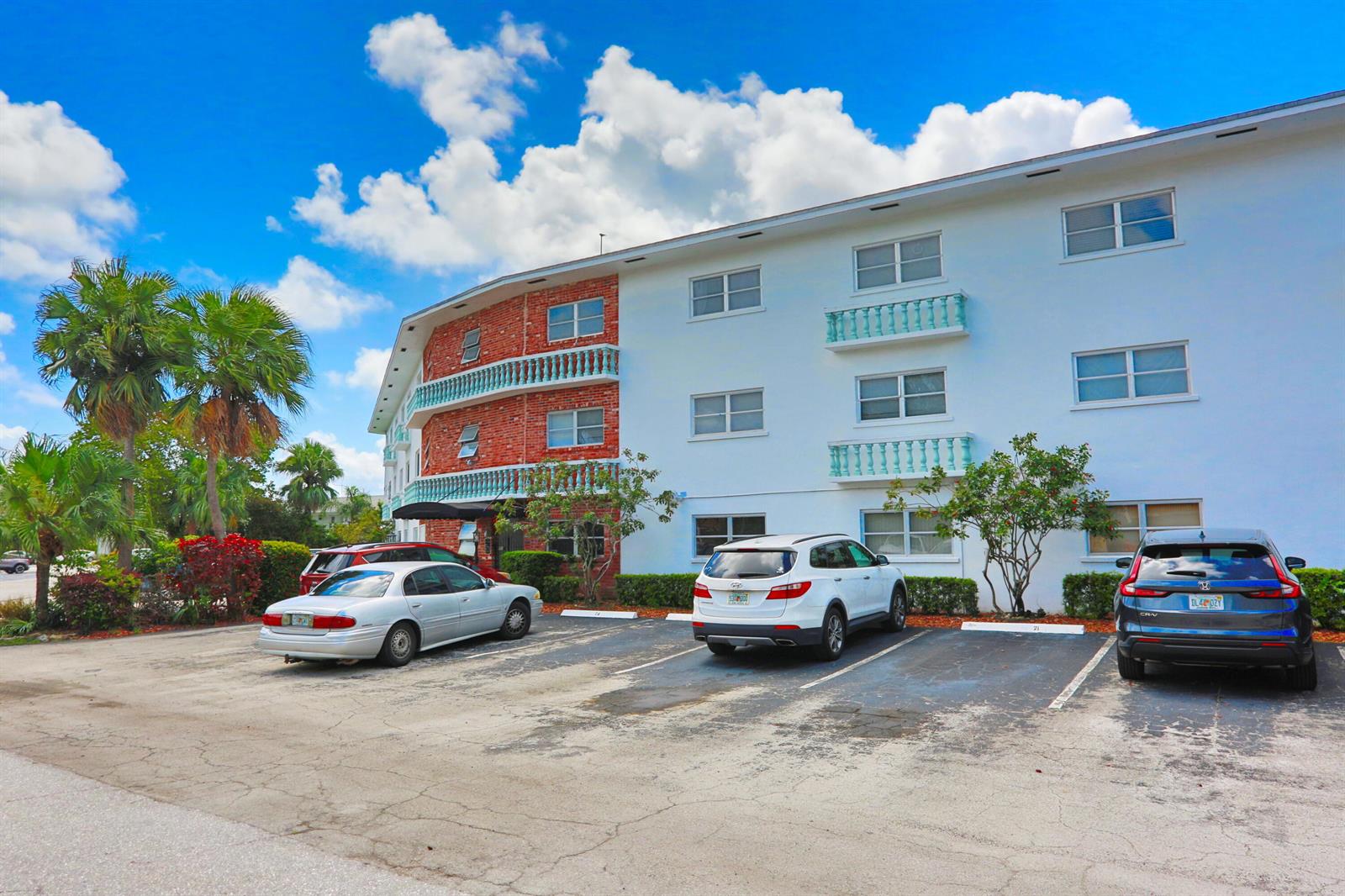 A three-story apartment building with brick and white stucco siding stands above a parking lot — 600 Pine Drive # 209, Pompano Beach FL 33060, POMPANO BEACH, FL