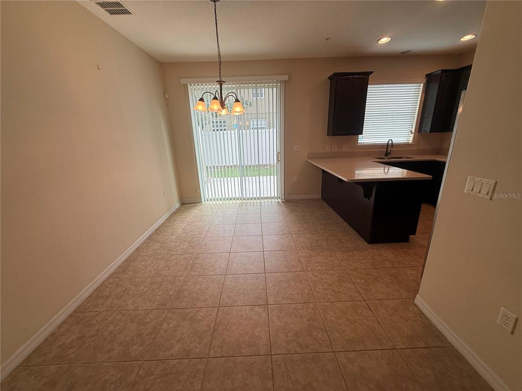 A dining area with tile flooring, a hanging light fixture, and a sliding glass door — 9460 STRONGBARK LANE, ORLANDO, FL