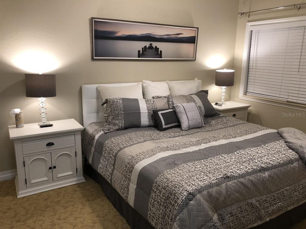 A bedroom features a bed with a patterned gray comforter, white headboard, and two nightstands — 7604 CABANA CT UNIT 303, REUNION, FL