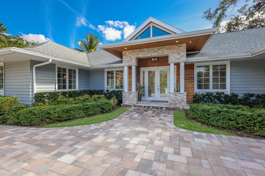 A single-story house with light blue siding, a stone-pillared entryway, and a paved driveway — 1253 N BASIN LANE, SARASOTA, FL