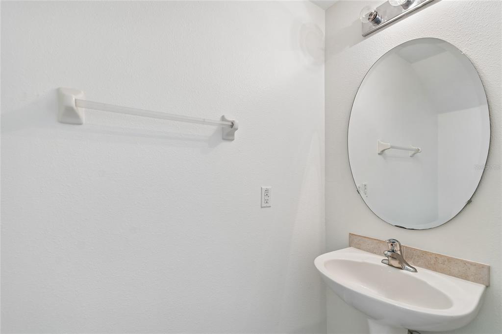 A bathroom features a pedestal sink, an oval mirror, and a wall-mounted towel bar — 4084 PITCH PINE CIRCLE, OVIEDO, FL