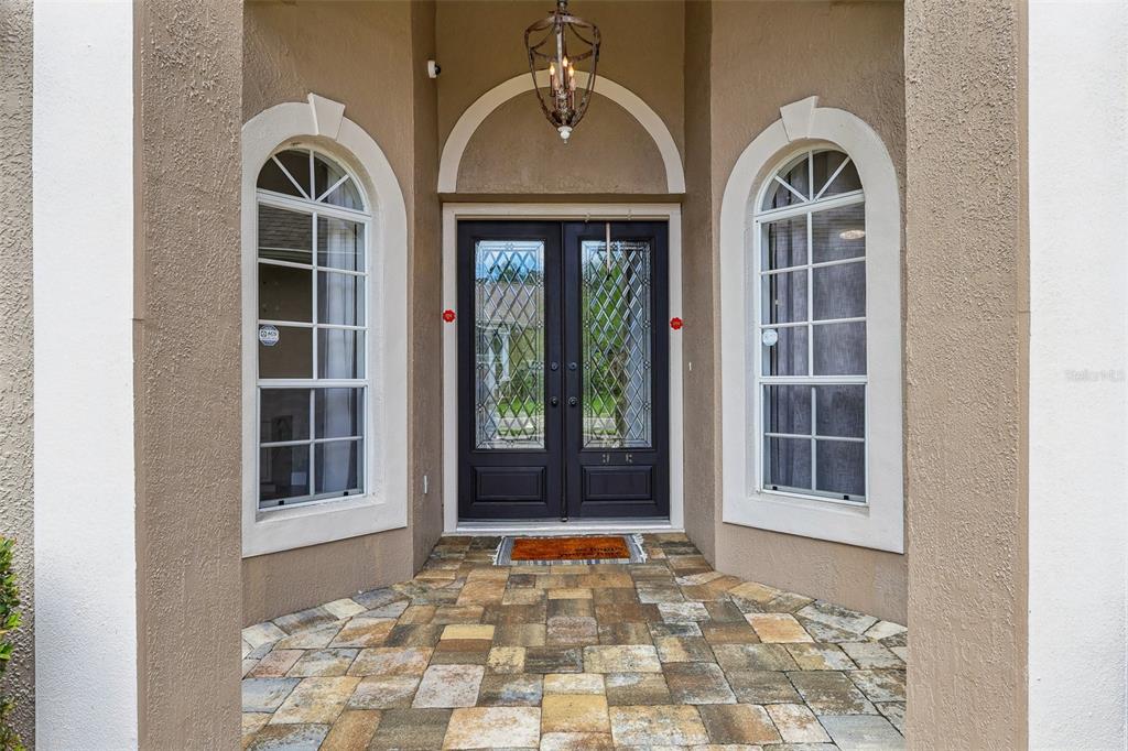 A front entryway features a double door with glass inserts flanked by two arched windows — 2728 RUNNING SPRINGS LOOP, OVIEDO, FL