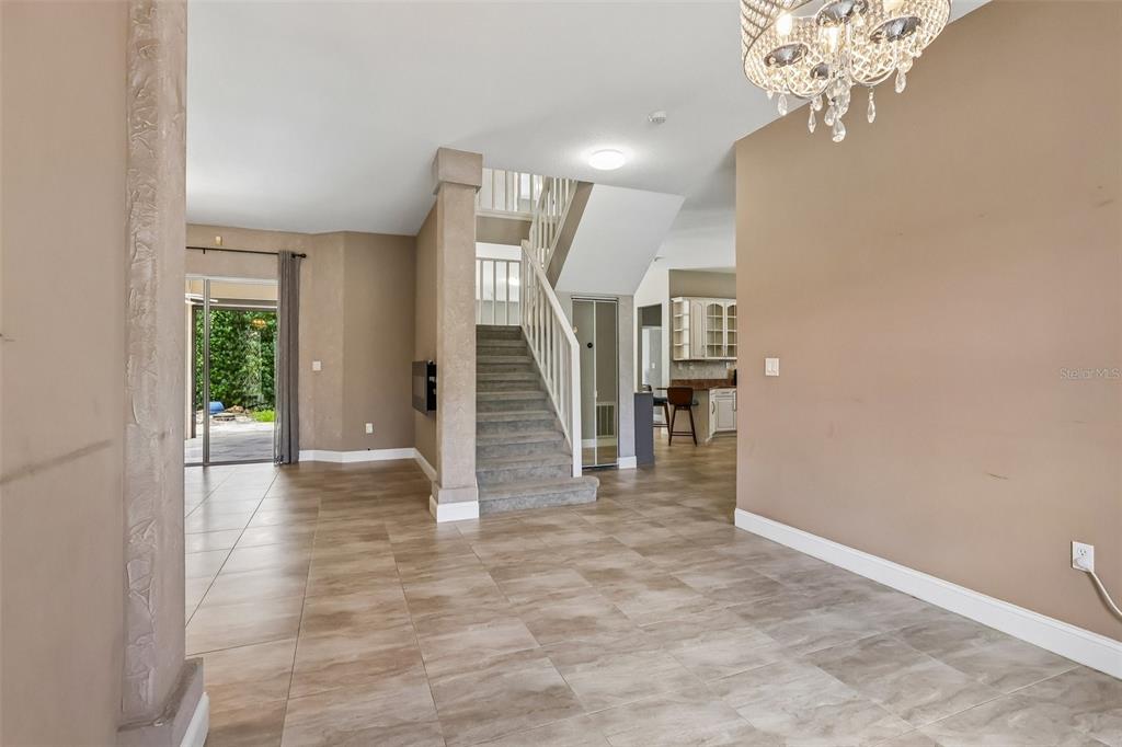 A tiled foyer features a staircase, a crystal chandelier, and a view into the kitchen — 2728 RUNNING SPRINGS LOOP, OVIEDO, FL