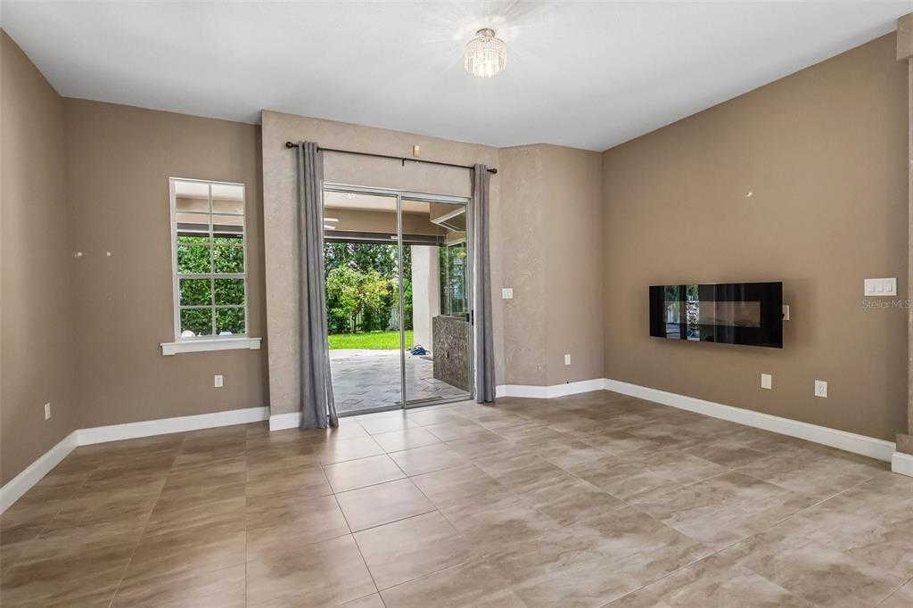 A living room with tile flooring, a wall-mounted fireplace, and sliding glass doors to a patio — 2728 RUNNING SPRINGS LOOP, OVIEDO, FL