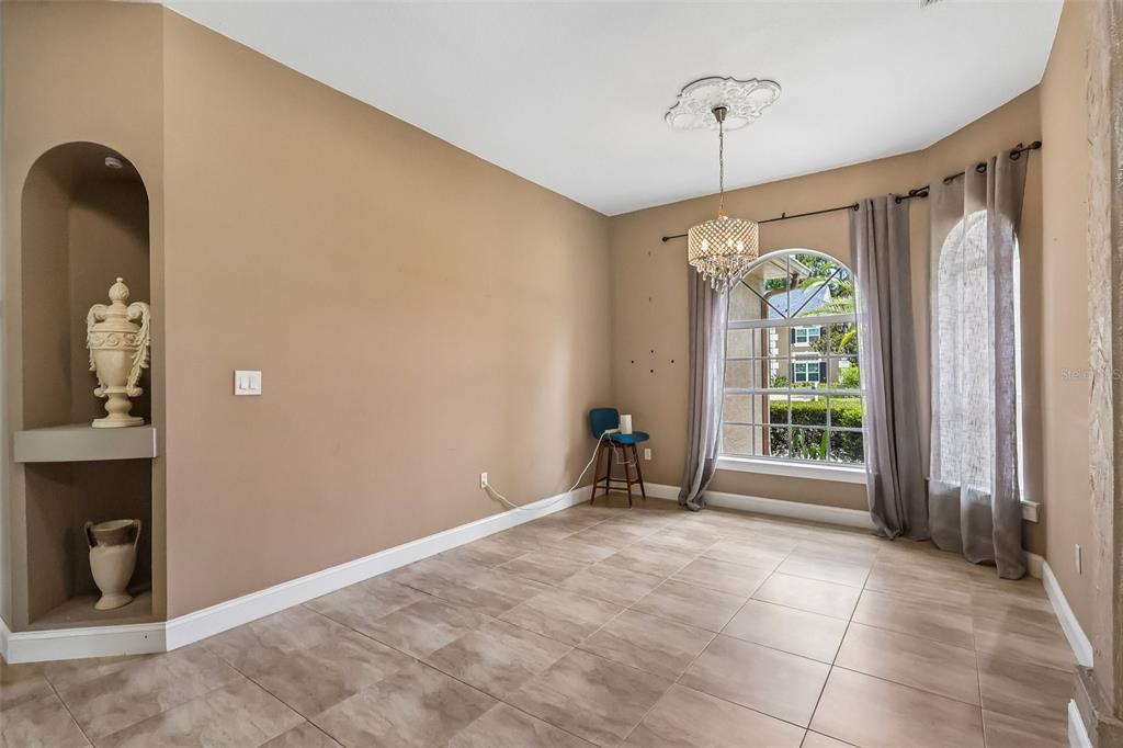 A dining room with tan walls, tile flooring, an arched niche, and a crystal chandelier — 2728 RUNNING SPRINGS LOOP, OVIEDO, FL
