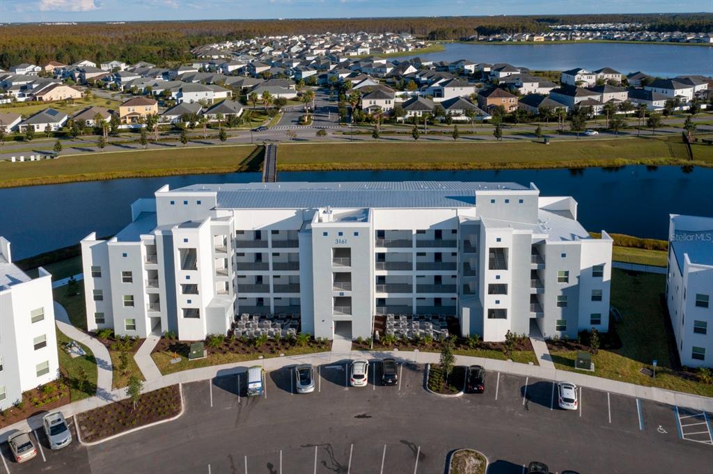 An aerial view of a multi-story white apartment building with a parking lot — 3161 PARADOX CIRCLE UNIT 304, KISSIMMEE, FL