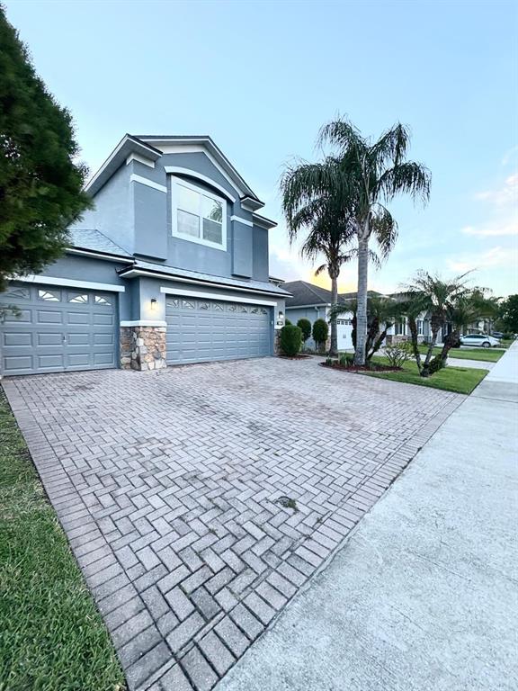 A two-story house with a gray exterior, stone accents, and a brick paver driveway — 1034 BELLA VIDA BOULEVARD, ORLANDO, FL