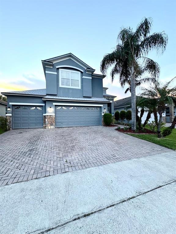 A two-story house with a gray exterior, stone accents, and a paved driveway — 1034 BELLA VIDA BOULEVARD, ORLANDO, FL