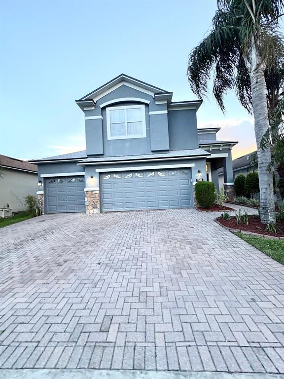 A two-story house with a gray exterior, stone accents, and a paved driveway — 1034 BELLA VIDA BOULEVARD, ORLANDO, FL