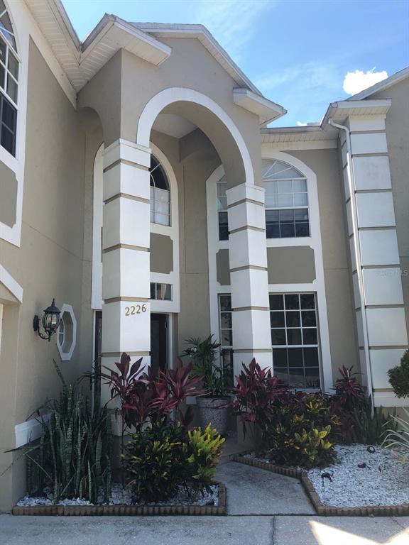 The exterior of a two-story house features a covered entryway with white columns and landscaping — 2226 WESTBOURNE DRIVE, OVIEDO, FL