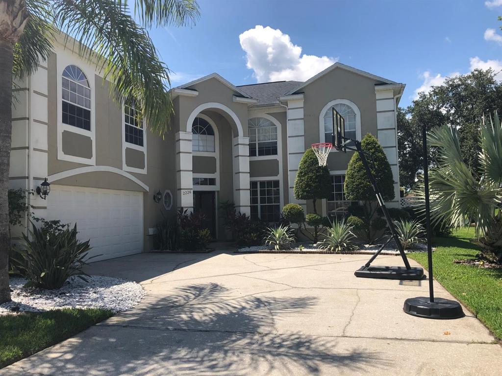 A two-story house with a beige exterior, white trim, a garage, and a basketball hoop — 2226 WESTBOURNE DRIVE, OVIEDO, FL