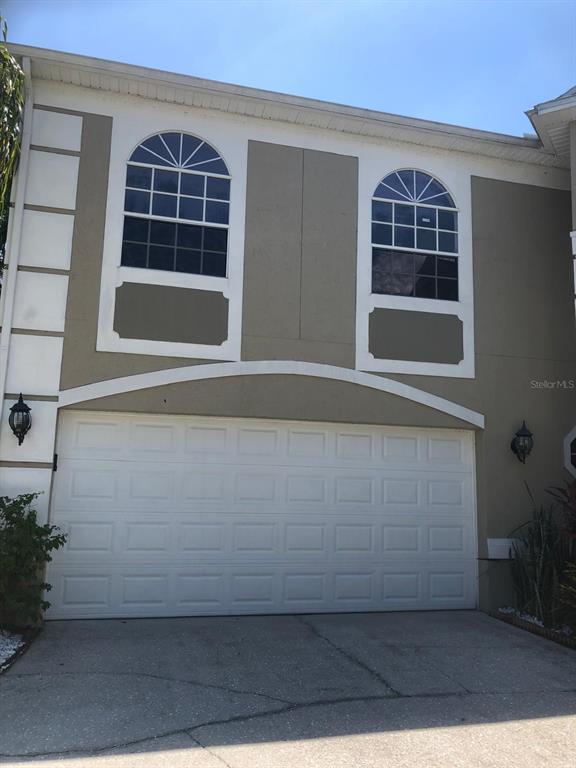 A two-story house exterior features a white garage door and two arched windows above — 2226 WESTBOURNE DRIVE, OVIEDO, FL