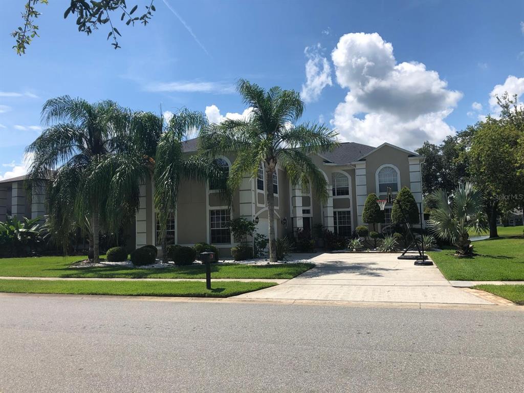 A two-story suburban house with a paved driveway, palm trees, and a basketball hoop — 2226 WESTBOURNE DRIVE, OVIEDO, FL
