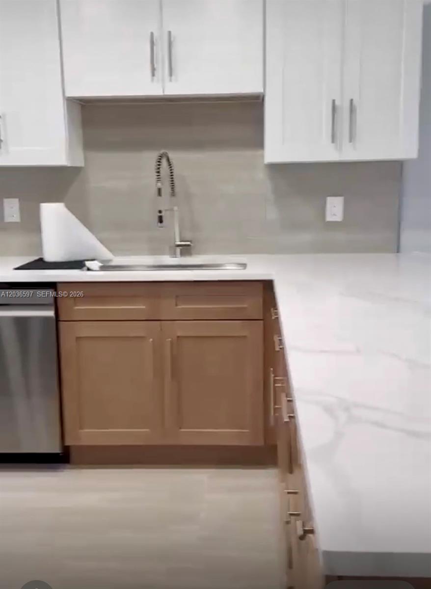 A kitchen features white upper cabinets, light wood lower cabinets, and white marble-look countertops — 2940 N Course Dr # 311, Pompano Beach FL 33069, POMPANO BEACH, FL