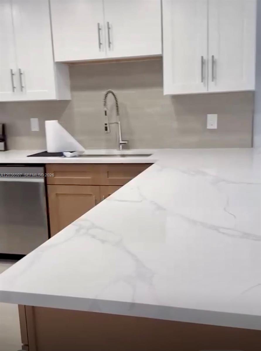 A kitchen features white upper cabinets, wood-toned lower cabinets, and a white marble-patterned countertop — 2940 N Course Dr # 311, Pompano Beach FL 33069, POMPANO BEACH, FL