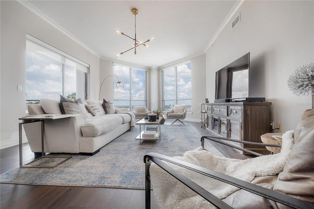 A modern living room features a white sofa, a television console, and floor-to-ceiling windows — 449 S 12TH STREET UNIT 2501, TAMPA, FL