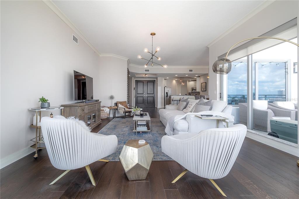A modern living room features white armchairs, a sectional sofa, and dark hardwood floors — 449 S 12TH STREET UNIT 2501, TAMPA, FL