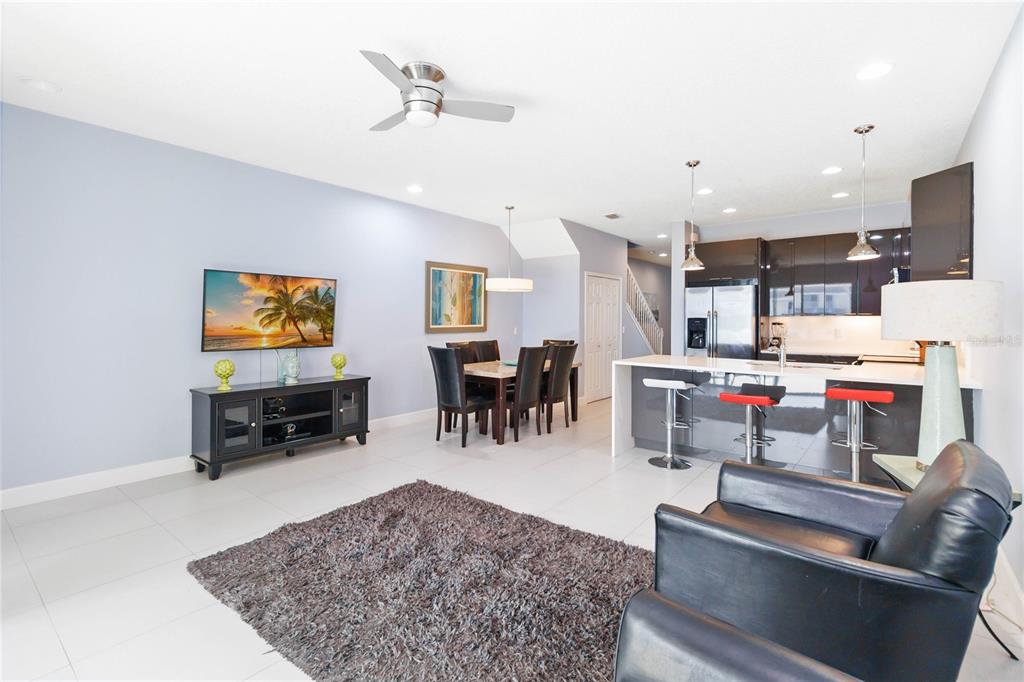 An open-concept living and dining area features tile flooring, a kitchen island, and modern cabinetry — 17416 PLACIDITY AVENUE, CLERMONT, FL