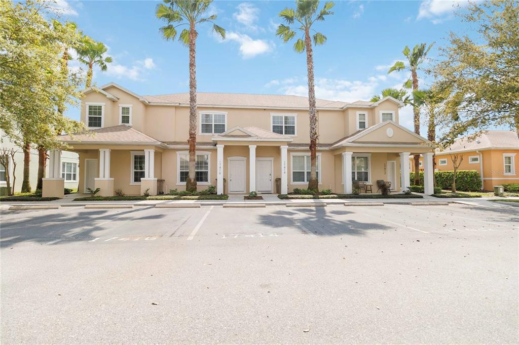 A multi-unit residential building with beige stucco siding, palm trees, and a paved parking lot — 17416 PLACIDITY AVENUE, CLERMONT, FL